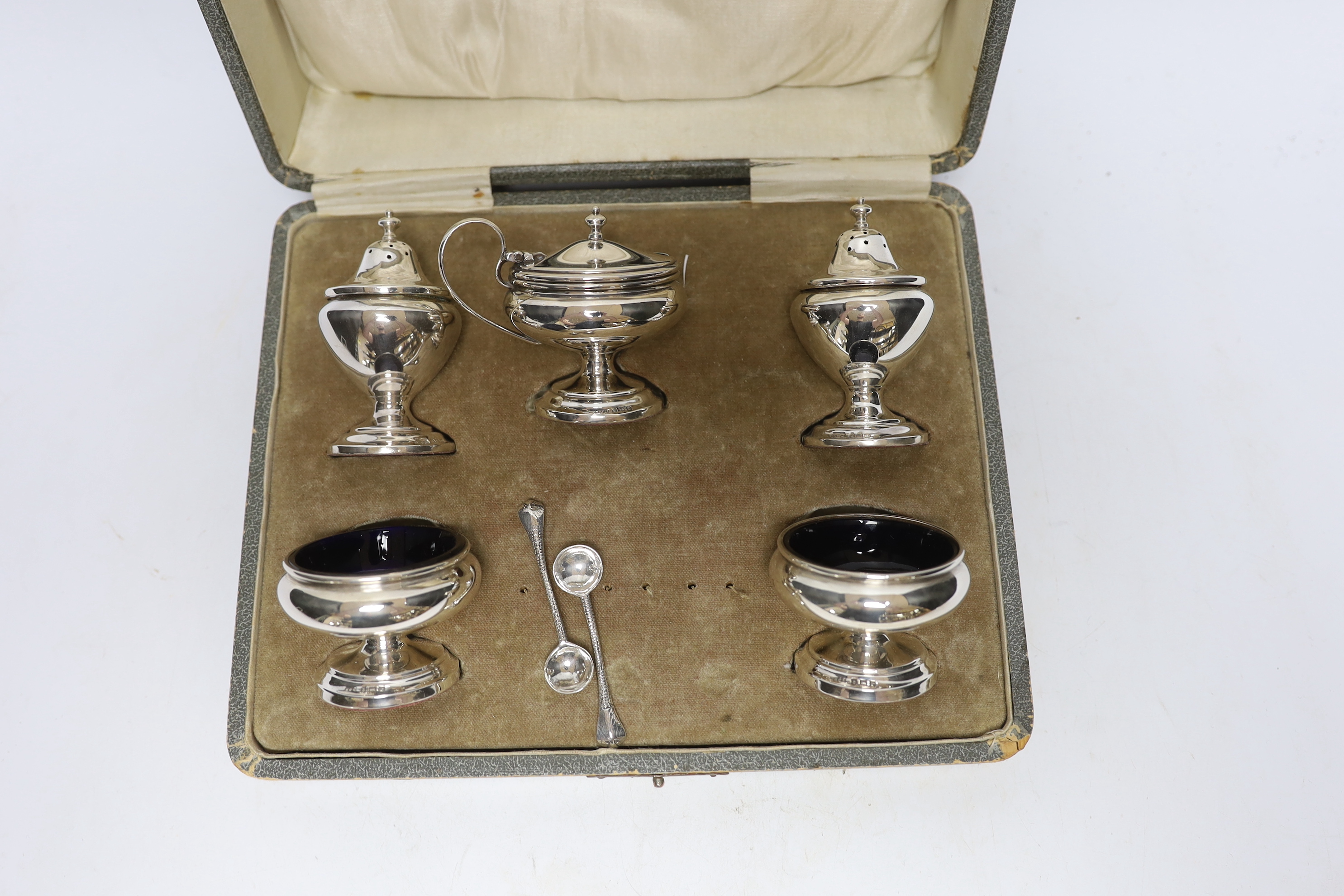 A cased George V silver five piece condiment set, Henry Clifford Davies, Birmingham, 1913 & 1917, with two associated plated spoons.
